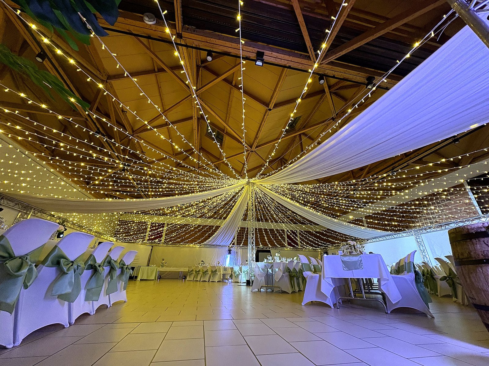 Salle de réception dressée avec structure lumineuse en éventail au plafond, décoration de mariage BLK Production