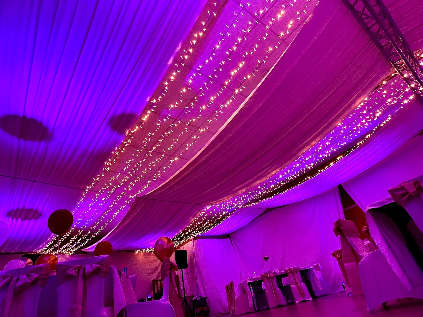 Drapé continu et guirlandes lumineuses sur une salle tout en longueur, éclairage rose et violet, décoration BLK Production
