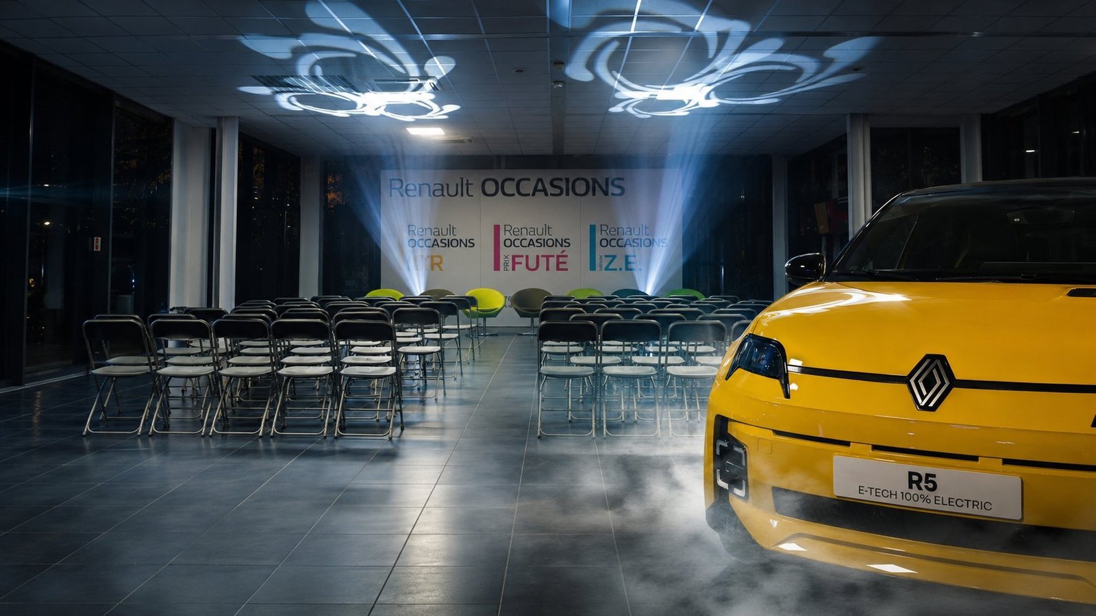 Spectacle d'inauguration de la nouvelle Renault 5 E-Tech 100% Electric jaune par BLK Production, gobos personnalisés au plafond projetant le logo Renault, faisceaux lumineux, fumée lourde au sol, fond Renault Occasions