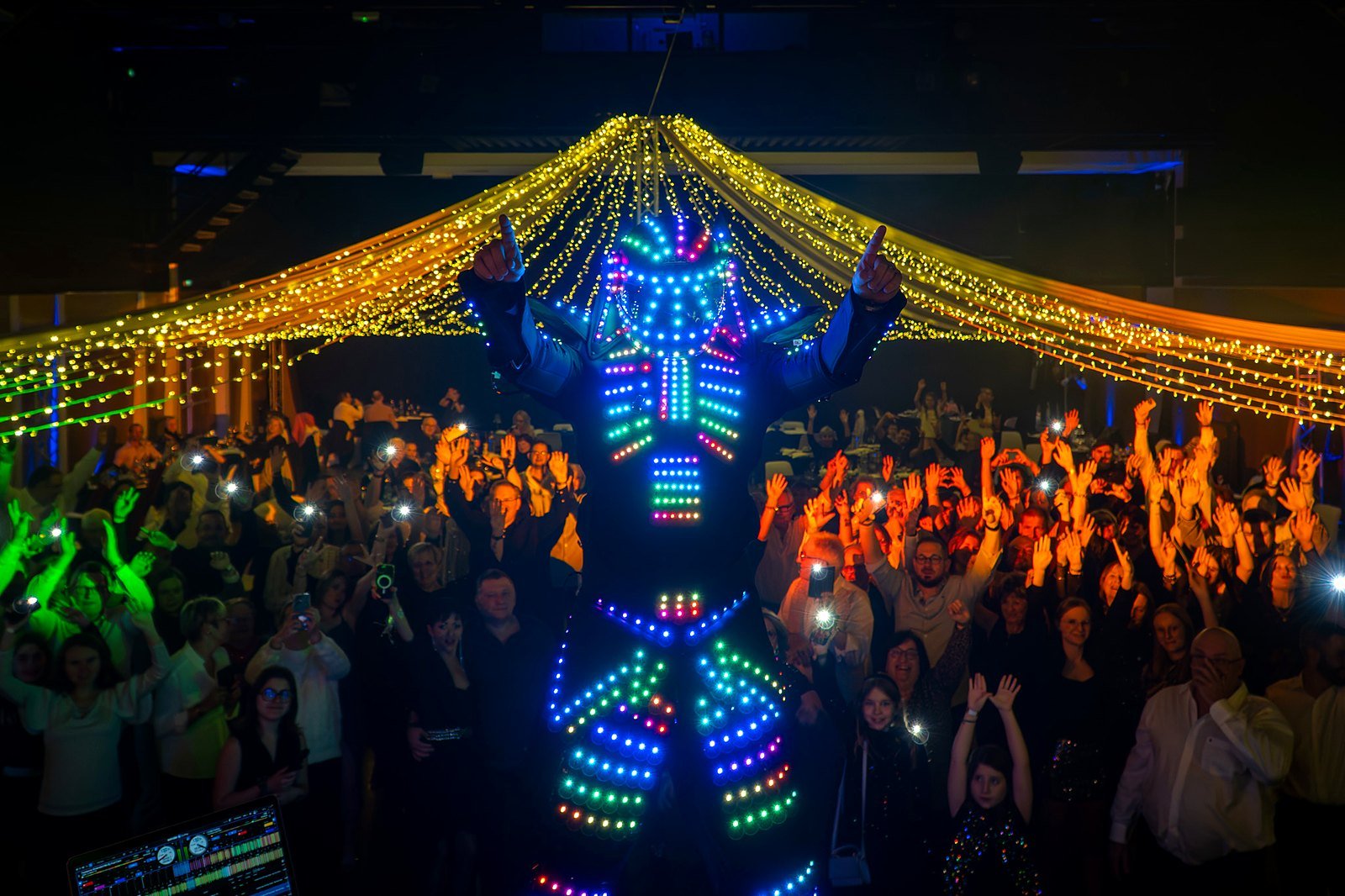 Robot LED géant lumineux dansant devant la foule en délire lors du réveillon du Nouvel An 2025 de BLK Production, sous le ciel de guirlandes dorées de la Comédie de Saint-Germain près de Troyes
