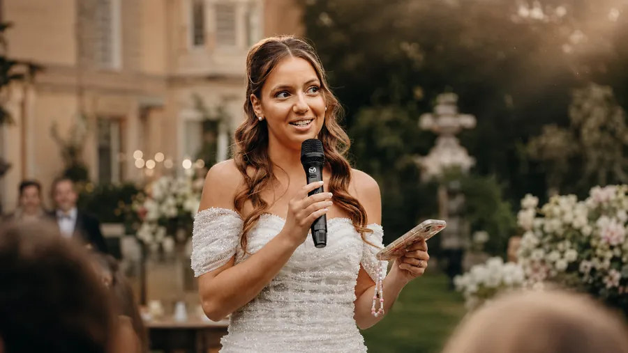 Discours de la mariée au micro sans fil dans le jardin d'un château