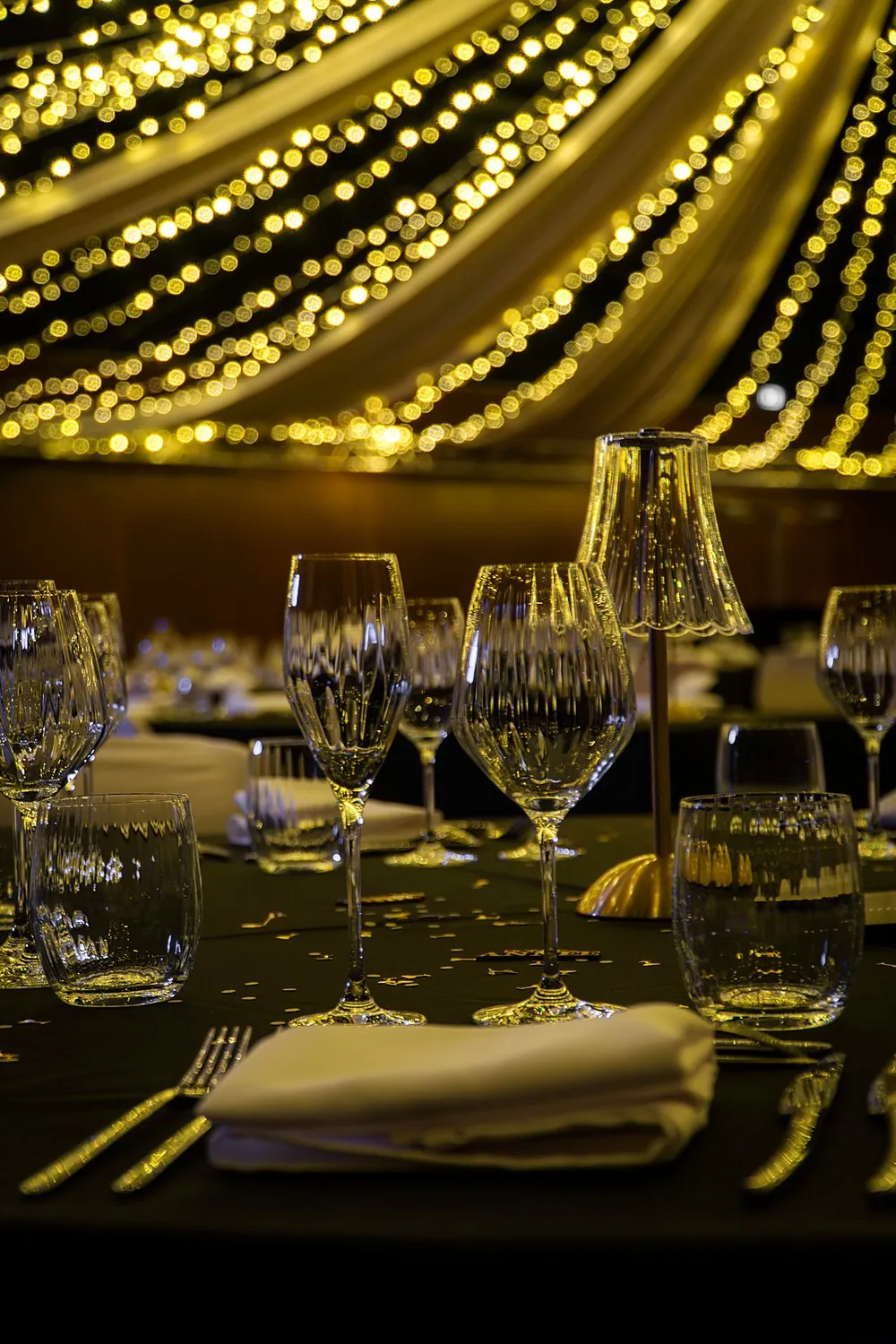Une table dressée pour le dîner du réveillon, verrerie fine et lumière dorée