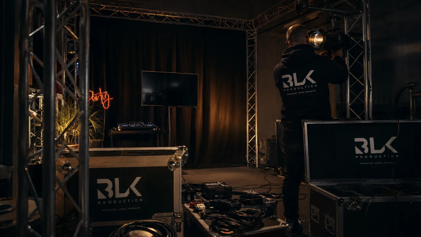 Technicien BLK Production réglant un projecteur au showroom de La Chapelle-Saint-Luc, entre structure aluminium et flight cases