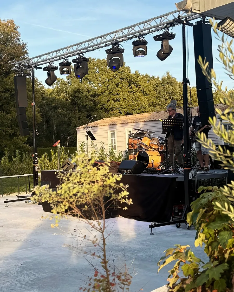 Scène montée sur la dalle en fin de journée, structure, lyres et line array, balances du groupe